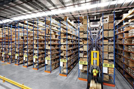 Narrow aisle pallet racking system in a high-density warehouse with labelled bays and forklift access for efficient inventory management.