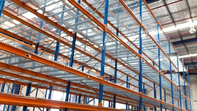 Industrial pallet racking system with steel mesh decking in a warehouse, designed for enhanced fire safety and airflow.