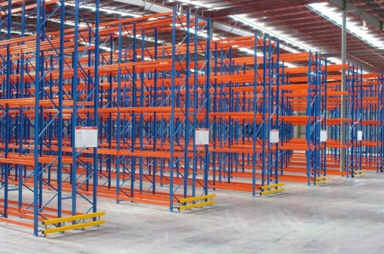 Empty selective pallet racking system with blue uprights and orange beams in a large warehouse, ready for high-capacity pallet storage installation.