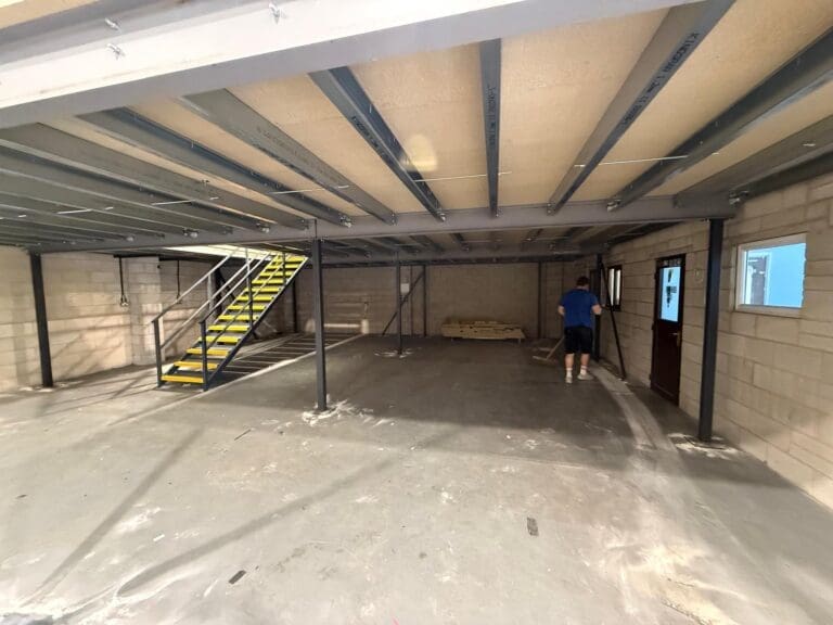 View beneath the newly installed mezzanine floor in a warehouse in Chesterfield, showing steel supports and access staircase.
